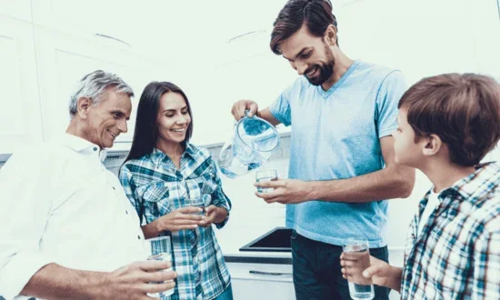 Family in a kitchen pouring glasses of water from a pitcher (illustrative photo, not a product photo)